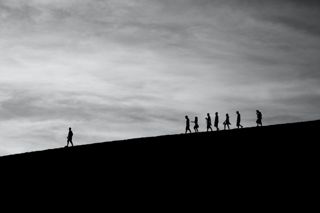 silhouette of people walking on ridge of hill